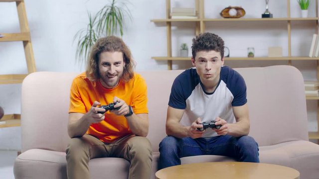 happy man playing video game with upset friend 