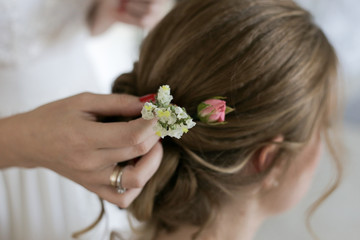 bridesmaid inserts flowers into bride's hair