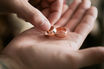 a man holds wedding rings in his palm and takes them with his other hand