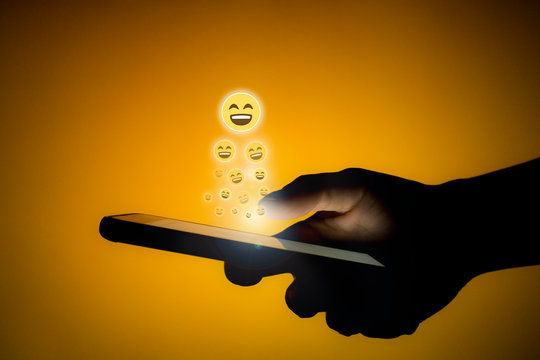 Human using phone sending smiley emojis