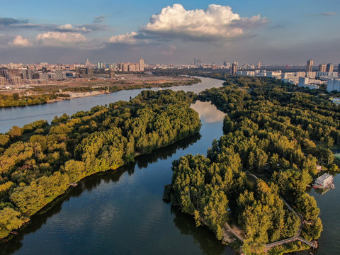 Aerial photo of Moscow river and beautiful green nature around. Summer city in the background.