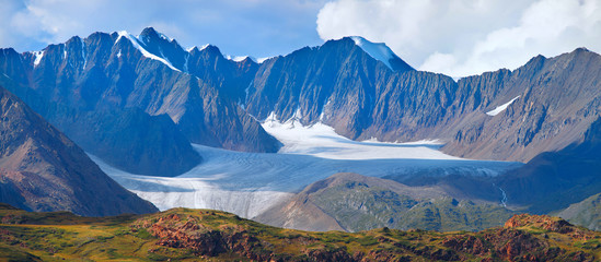 Panoramic mountain view. Large glacier, rocky peaks. Traveling in the mountains, mountaineering.