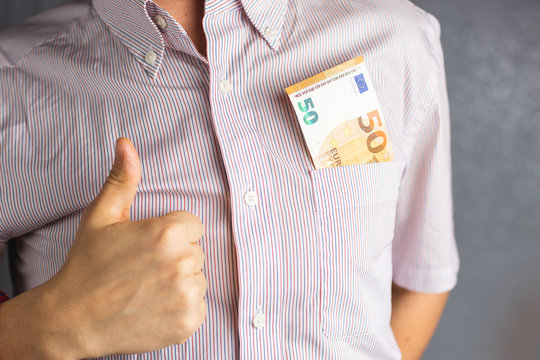 A man in a bright shirt holds money in his breast pocket and shows his thumb up. 50 Euro currency