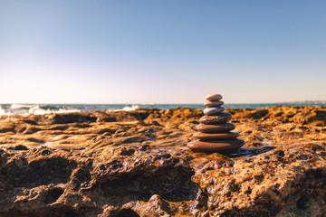 Fototapeta na wymiar Pyramid of stones for meditation lying on sea coast. Zen stones sunset sea peace of mind concept