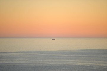 Boat in the sea on the horizon line. Golden gradient sky background. Fuji city, Japan. Horizontal shot.