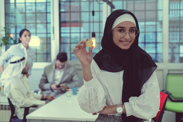 Young arabian muslim woman in hijab black clothes hold in hand holding bitcoin. Cryptocurrency exchange