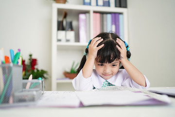 Little child girl concentrate and focusing to the homework for elementary school. thinking seriously for Educational solution concept.