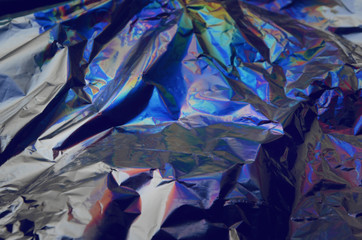 Holographic iridescent crumpled foil texture background