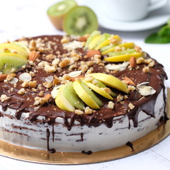 Tasty piece of chocolate cake with fruits, chocolate, apple, kiwi on cup of coffee americano, white background. Organic dessert sugarless. Healthy eating.