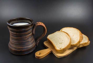 Milk in a clay mug and toasted bread on a wooden board