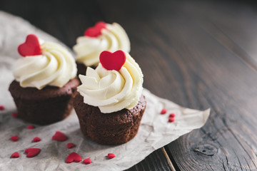 Valentine cupcakes, decorated with sweet hearts on dark wooden table.