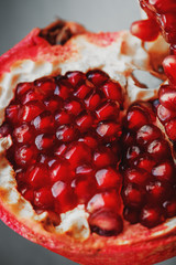Juicy seeds of fresh fruit of the opened pomegranate on a black background close-up.