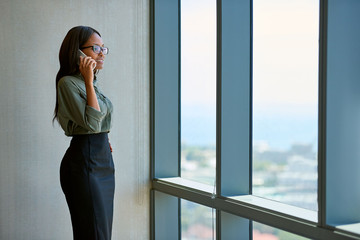 Executive talking on a cellphone by windows in an office