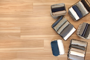 Vertical tidying up storage. Neatly folded clothes neutral colors in the metal black baskets for wardrobe. Wooden background. Nordic style.