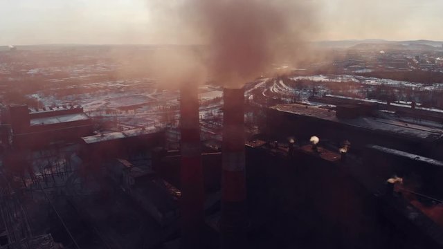 Epic aerial of high pipes with red smoke emission. Plant pipes pollute atmosphere. Industrial factory pollution, smokestack exhaust gases. Industry zone, red and white pipes, thick smoke plumes