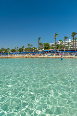 CYPRUS, NISSI BEACH - MAY 12/2018: Tourists relax and swim on one of the most popular beaches on the island.