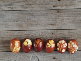 Easter eggs painted onion peel with a pattern of fresh herbs on a wooden ancient background. We color the eggs according to the old eco-friendly method with peeled onions.