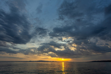 Beautiful dramatic early morning sunrise landscape. Cloudy sky and sunny water of Aegean sea in Greece, Chalkidiki. Horizontal color photography.