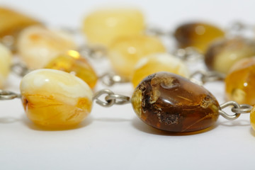 Amber beads of yellow color with inclusions on a white background. Sun stone on a light gray background. Macro shot of a natural mineral. Digging jewelry. Fossilized petrified ancient resin