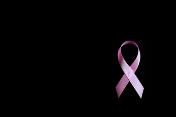 pink ribbon, a symbol of breast cancer awareness, isolated on a black background. space for text