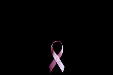 pink ribbon, a symbol of breast cancer awareness, isolated on a black background. space for text