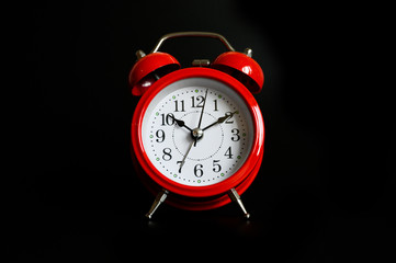 red round analog alarm clock isolated on black background. time 10:10