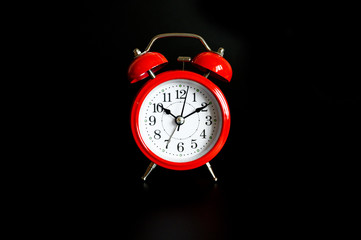 red round analog alarm clock isolated on black background. time 10:10
