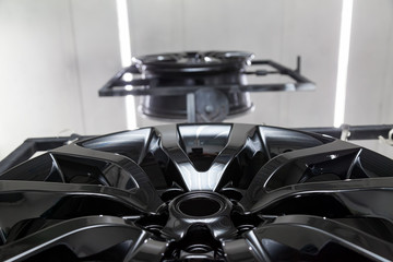 A Two black painted aluminum alloy wheel is mounted on a special frame during drying in a chamber...