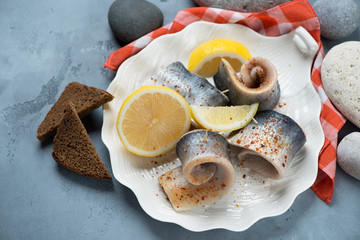 Shell-shaped plate with herring fillet, studio shot on a grey concrete background with pebble...