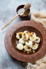 Clay plate with boiled cottage cheese dumplings over beige stone background, vertical shot