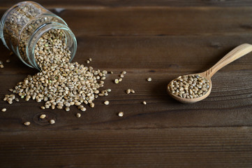 hemp seeds spilling out of the glass jar and wooden rustic spoon on a wooden background. space for...