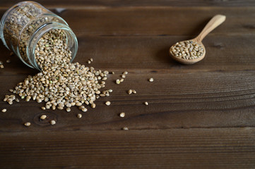 hemp seeds spilling out of the glass jar and wooden rustic spoon on a wooden background. space for text