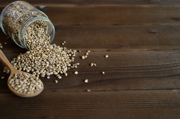 hemp seeds spilling out of the glass jar and wooden rustic spoon on a wooden background. space for...