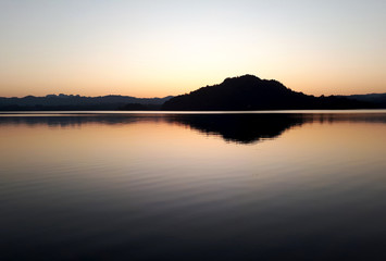 The silhouette of the mountain reflected on the evening water.