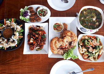Thai food lined up on a wooden table.
