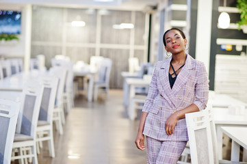 Charming african american woman in jacket posing at restaurant.