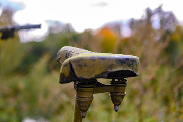 Mossy saddle of an abandoned weathered bike in a park.