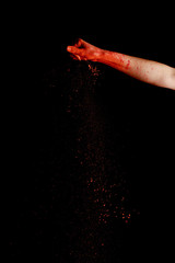 female hand with red colorful holi paint powder on black background