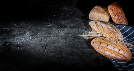 Assortment of baked bread and bread rolls on dark background