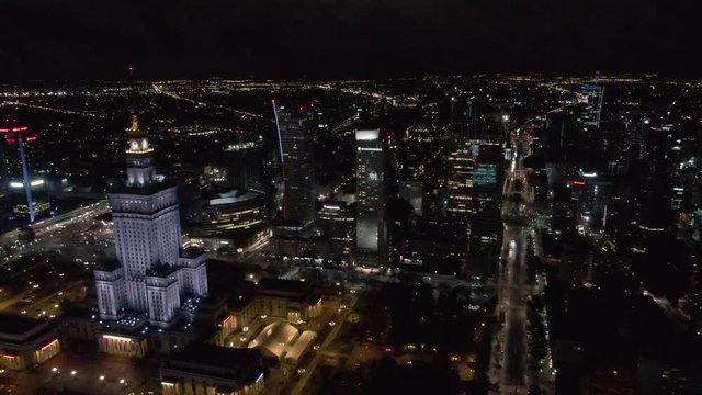 Drone shot of Palace of culture and science in Warsaw surrounded by other business buildings at night