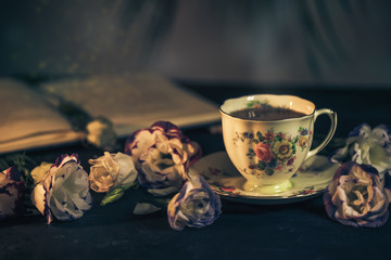Still life with vintage cup of tea, book and flowers