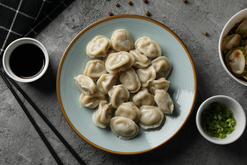 Composition with dumplings and soy sauce on grey background, top view