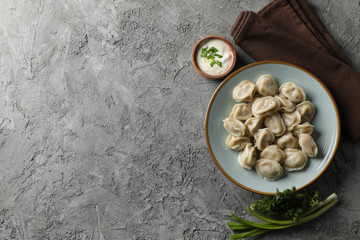 Plate with dumplings, towel and spices on grey background, top view