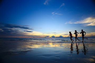 silhouettes of athletes running along the beach / sports summer in the warm sea, healthy rest, sports activity, summer vacation