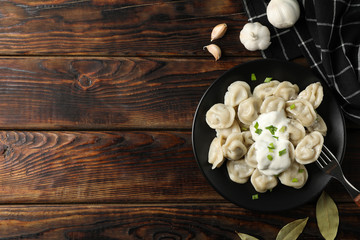 Plate with dumplings and towel on wooden background, top view