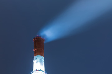 The illuminated red and white tube or pipe of the thermal power plant on the background of blue...