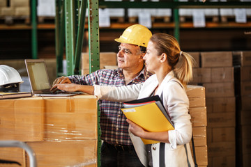 Female manager and warehouse worker checking list and inventory on the shelf in storehouse.	