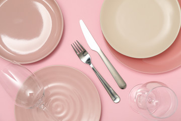 Table setting with wineglasses on pink background, top view