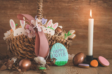 Happy Easter. Multicolored pastel easter cookies in a wicker basket  on a wood background