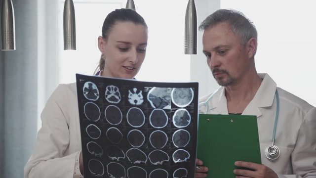 two professional doctor radiologist colleague discussing head brain skull x-ray shot. coworkers talking, analyzing photo. concept hospital, consultation, radiology. examine xray in clinic.